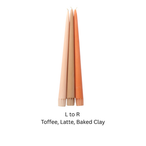 Three taper candles in warm neutral clay colors labeled 'L to R Toffee, Latte, Baked Clay' on a plain white background.