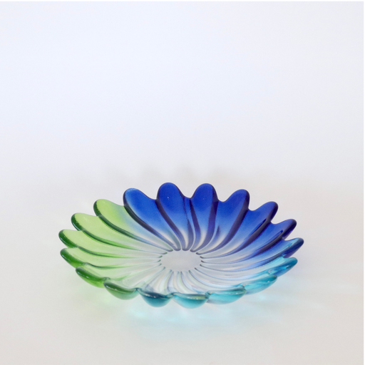 A shallow petal-shaped glass bowl with a blue-to-green gradient, photographed on a clean white background.