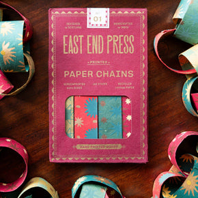 Pack of East End Press paper chains on a wooden surface with colorful paper chains around