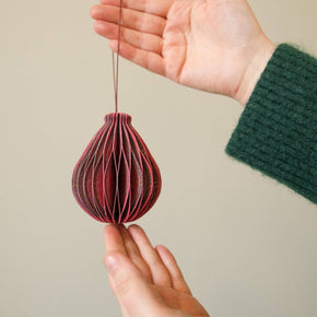 Hand holding a red woven ball against a beige background