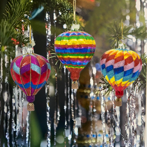 Colorful hot air balloon ornaments hanging on a tree with a blurred background.