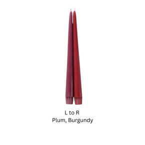 Two slim taper candles in plum and burgundy shades, shown side by side on a plain white background with the text 'L to R Plum, Burgundy' below.