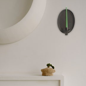 Decorative wall sconce with a green candle on a neutral background