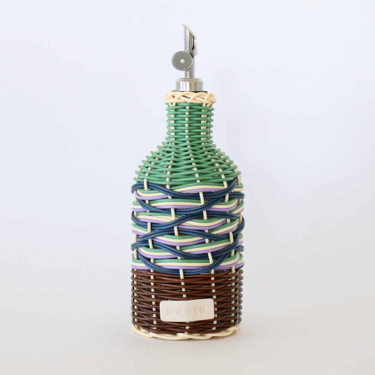 Decorative olive oil bottle with green, brown and navy woven design and metallic nozzle on a white background.