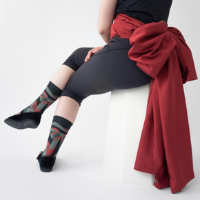 Woman in black leggings with red sash wearing Bonne Maison Ribbon socks on white backdrop.