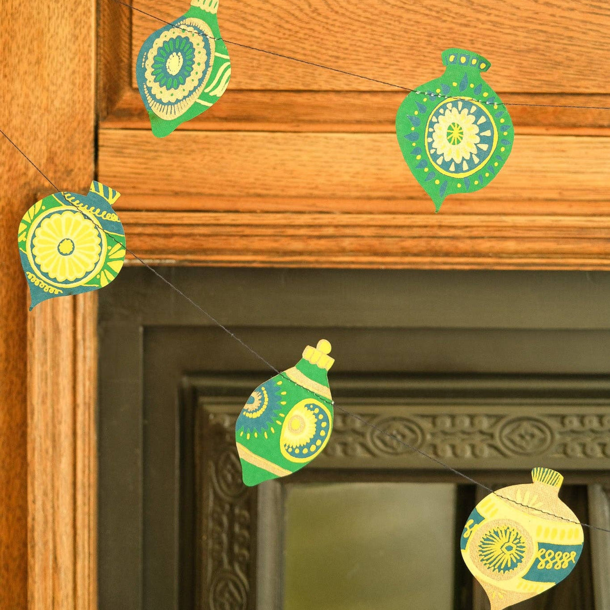 Decorative green and yellow ornaments hanging on a wooden wall.