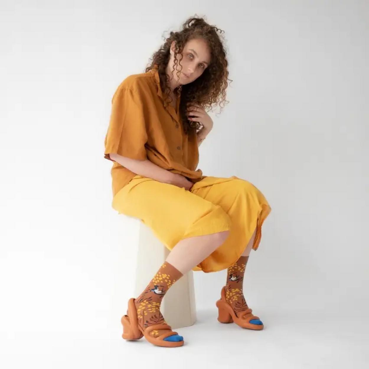Woman in yellow skirt wearing Caramel Mimosa Bonne Maison socks on white backdrop.
