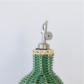 Close up of nozzle of Decorative olive oil bottle with green, brown and navy woven design and metallic nozzle on a white background