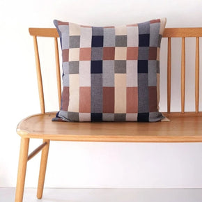 Checkered double cotton  pillow on a wooden bench against a white wall
