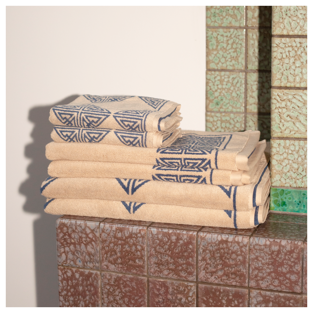 Autumn Sonata Bath Sheet - Agnes folded with hand towels on tiles shelf