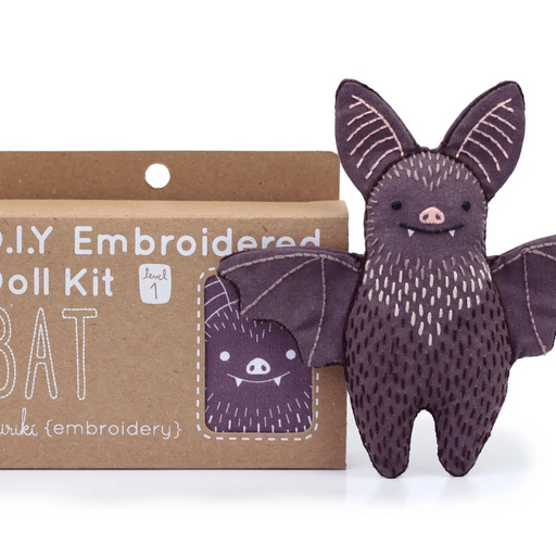 Embroidered bat toy next to its packaging on a white background