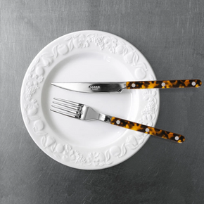 Sabre Paris Faux Tortoise knife and fork from 4 piece cutlery set, on white plate on steel benchtop.
