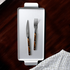 Sabre Paris Faux Tortoise knife and fork from 4 piece cutlery set, on silver tray on wood benchtop.