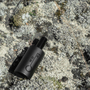 Black cylindrical EDP bottle with text on a textured stone surface