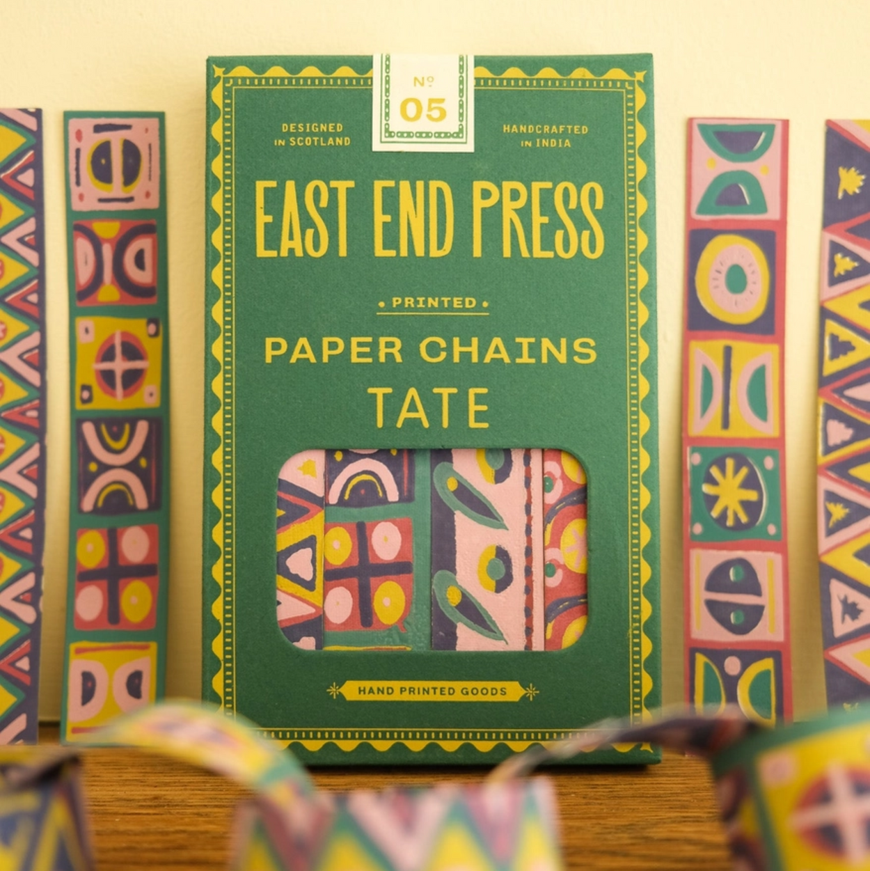 Packaging of East End Press paper chains with colorful geometric patterns on a wooden surface.