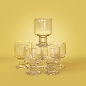Set of 6 clear glass goblets on a yellow background