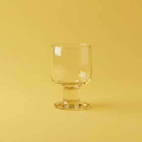Clear glass goblet on a yellow background