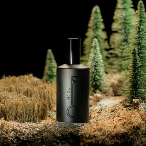 Black cylindrical EDP bottle with Fischersund logo on a forest floor