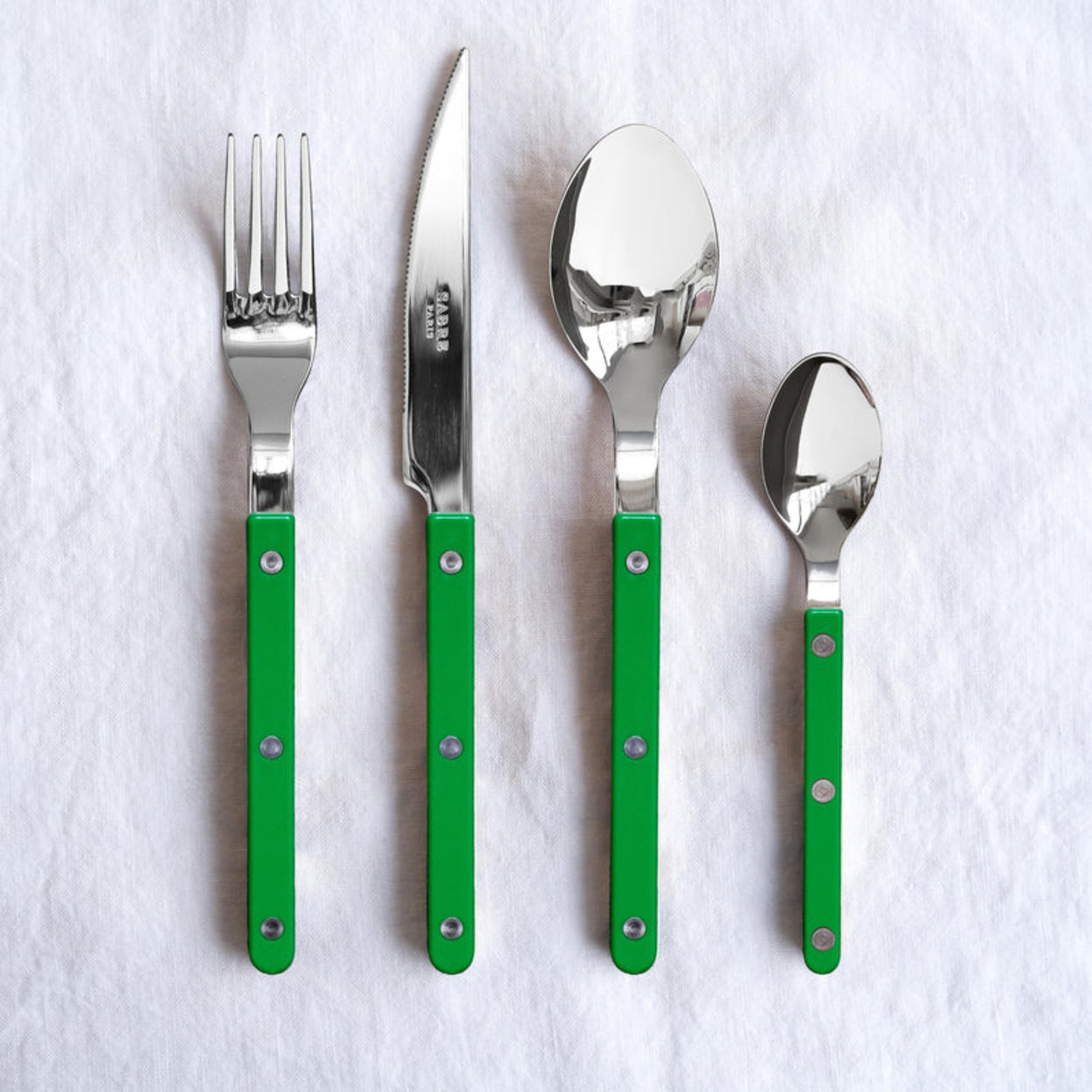 Set of stainless steel Sabre Paris cutlery with grass green handles on a white background