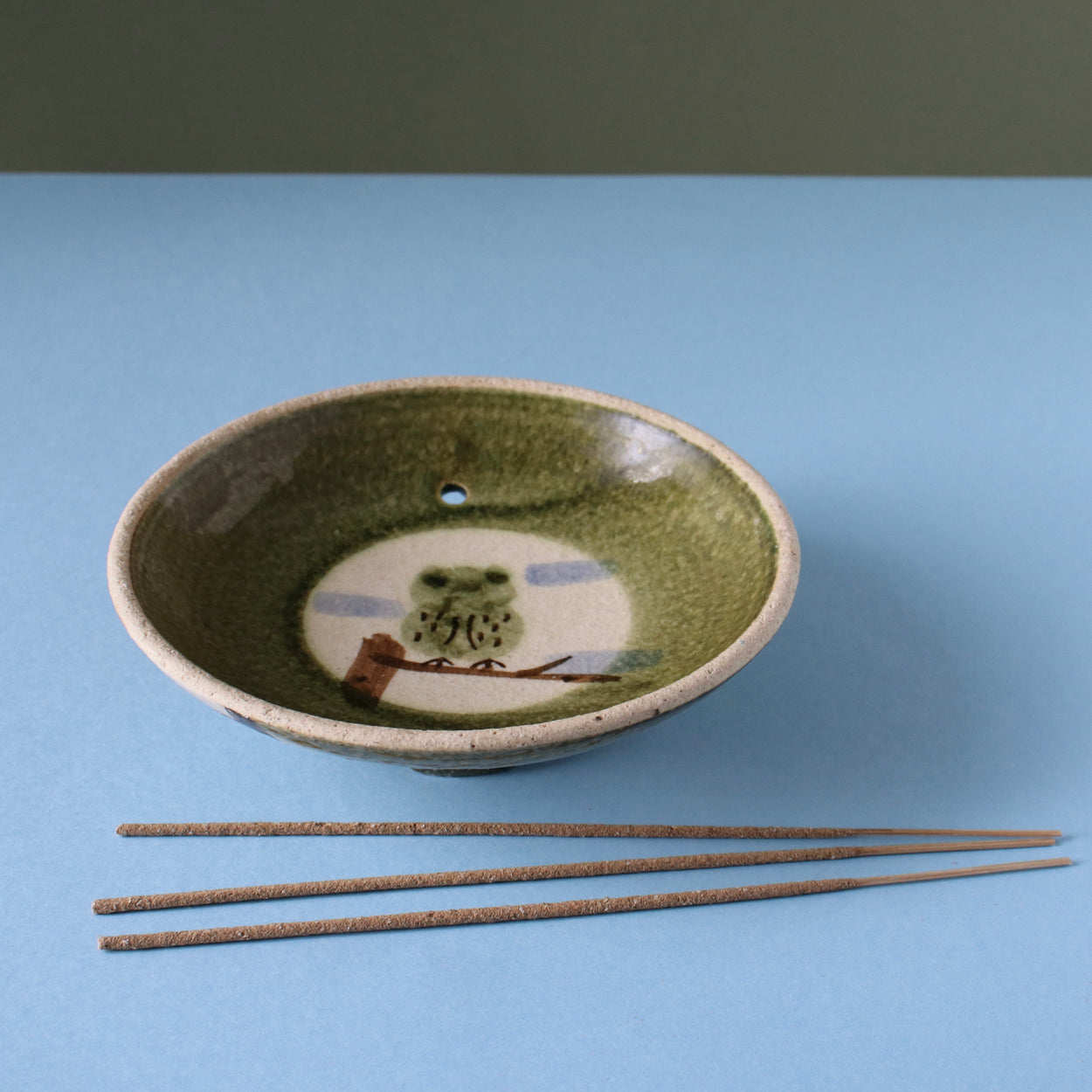 Vintage Japanese owl bowl incense holder with blue background with incense sticks