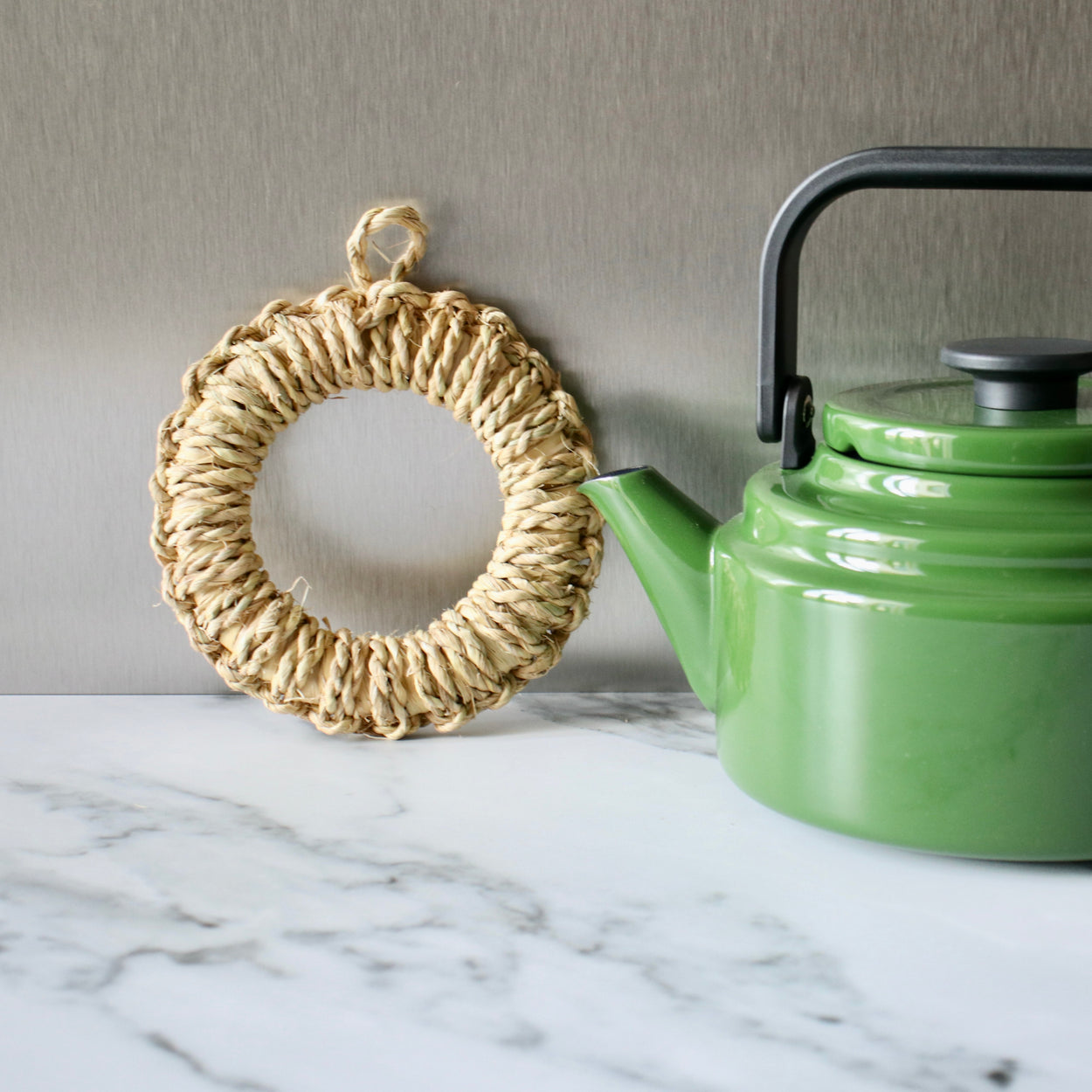 Japanese Woven Pot Holder leaning on marble bench with green Amu kettle.