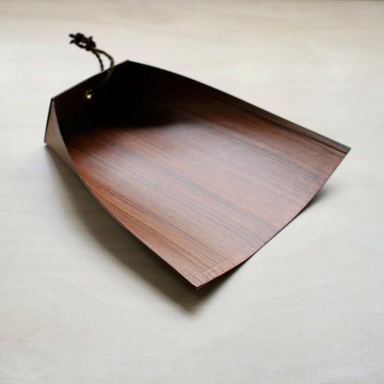 Side profile of Japanese Harimi Dustpan on pale wood background