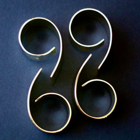 Side profile Vintage 2 sets of 4 silver plate napkin rings against dark blue backdrop.