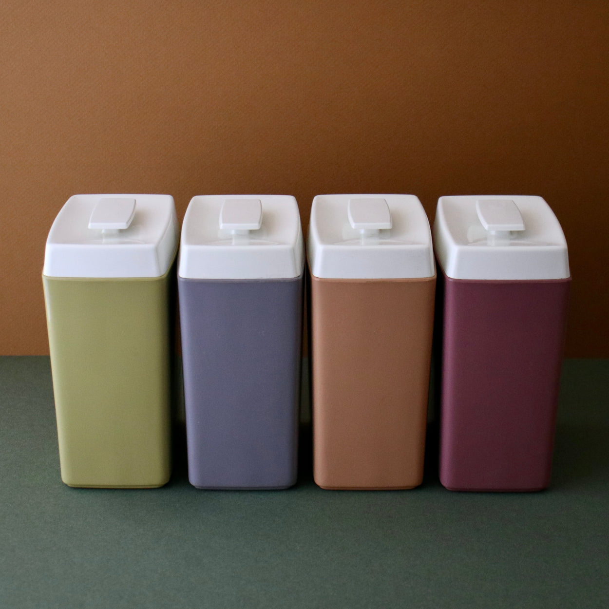 Vintage set of 4 Nylex Kitchen canisters against a brown and green backdrop.