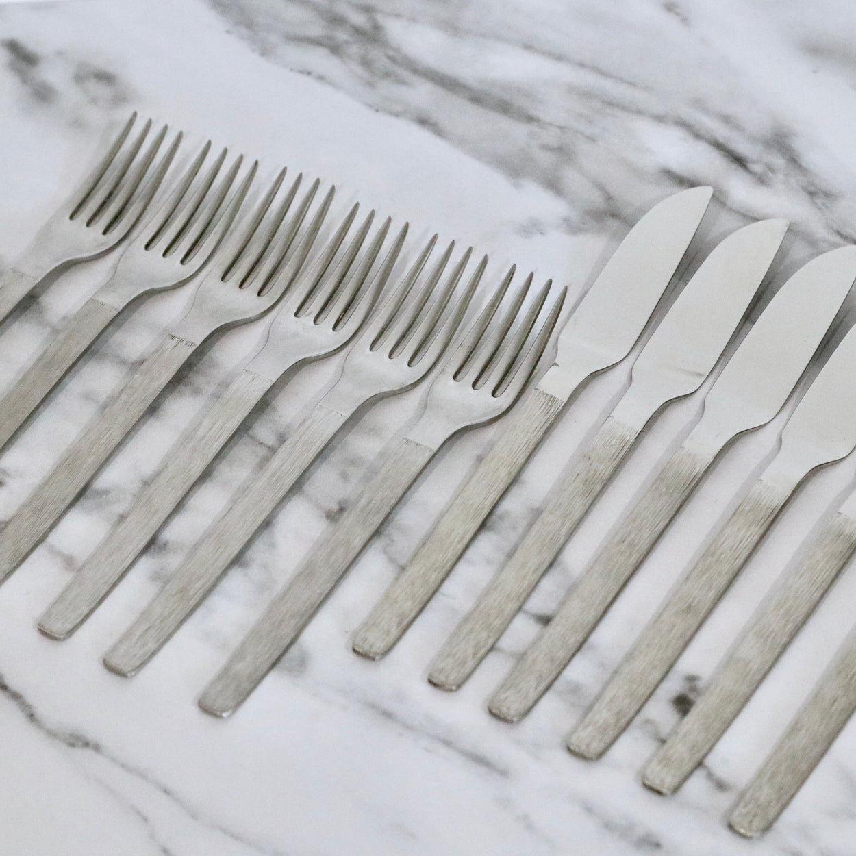 Vintage set of stainless steel flatware against a marble background.