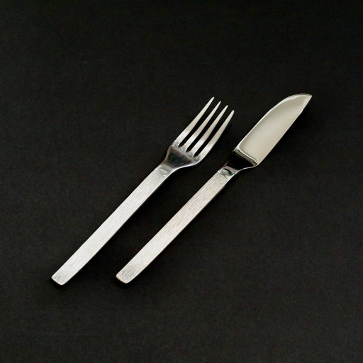 Vintage set of stainless steel flatware against a black background.