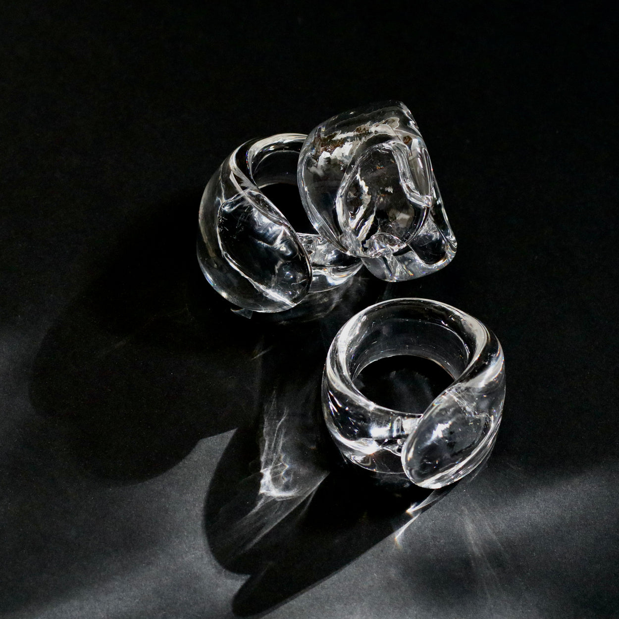 Vintage handmade glass napkin rings against a black background.