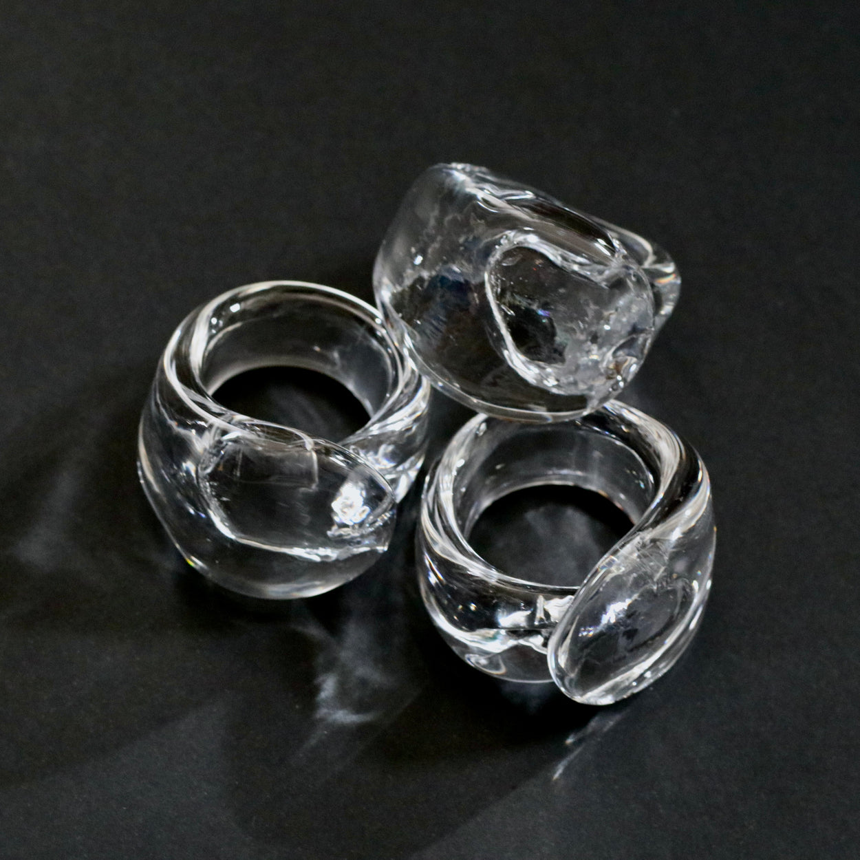 3 Vintage handmade glass napkin rings against a black background.