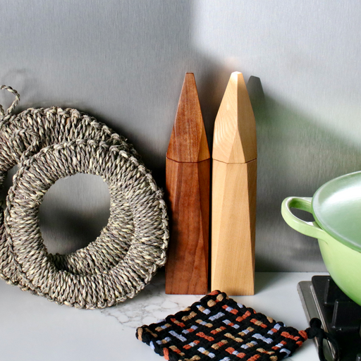 Wooden Martino Gamper Salt & Pepper Spitz, Japanese straw trivets and pot holder all on marble kitchen bench next to green pot.