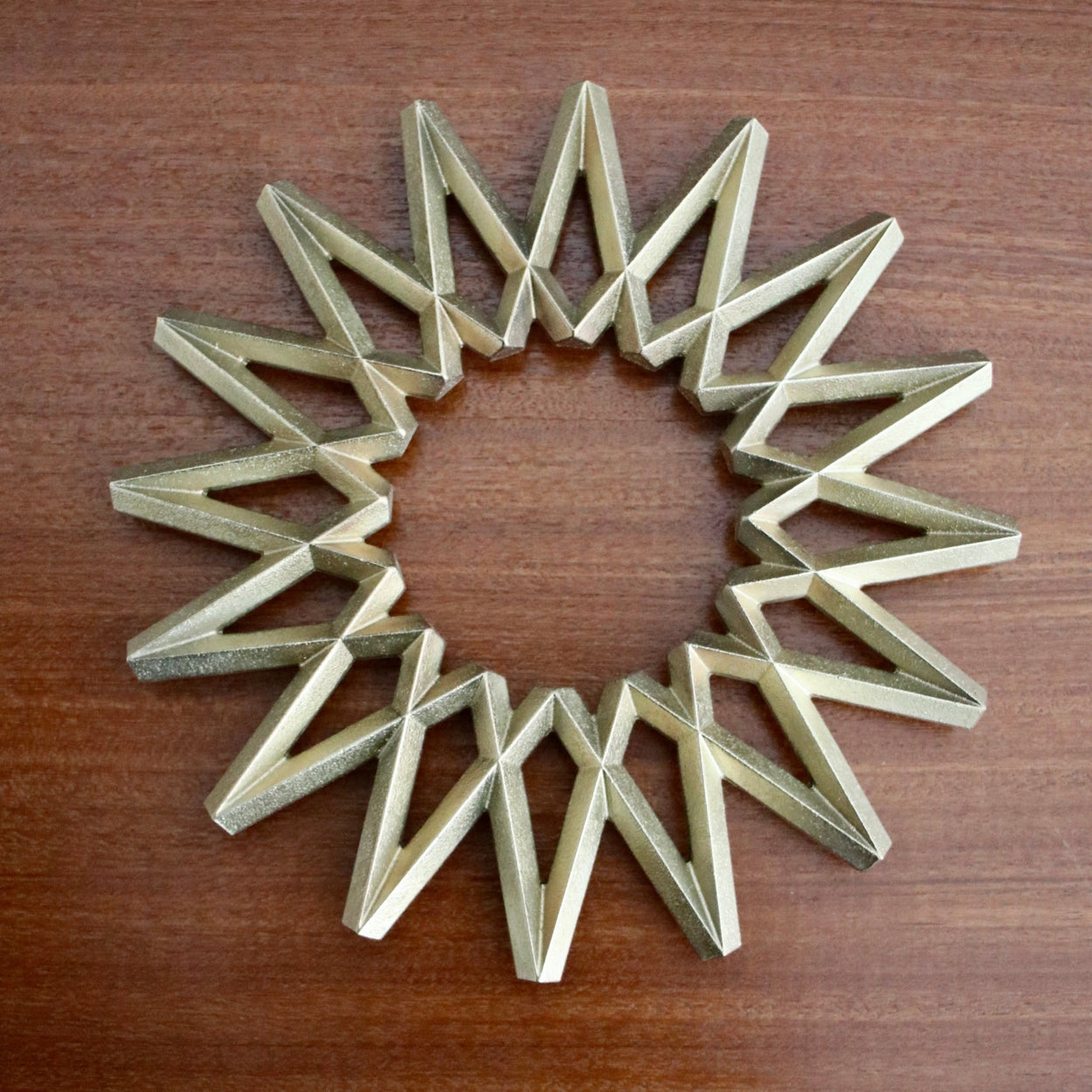 Futagami Brass Galaxy Trivet on wood background.