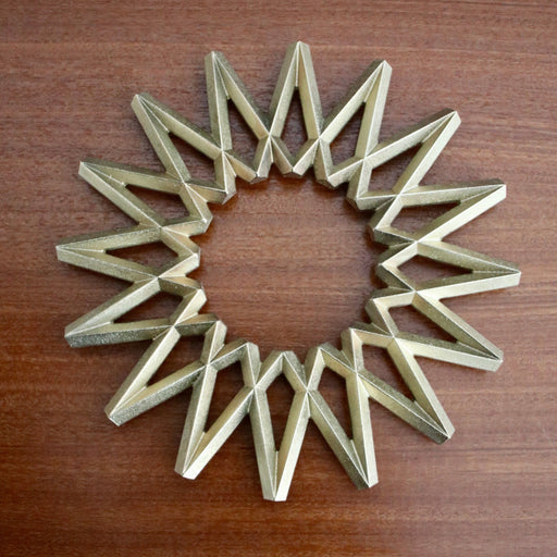 Futagami Brass Galaxy Trivet on wood background.