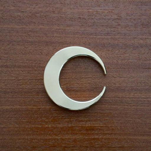 Futagami Crescent Bottle Opener on dark wood background.