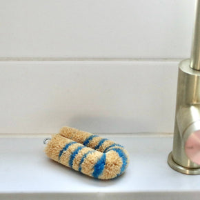 Blue Japanese Striped Tawashi pot scrub brush on white tile shelf with gold tapware.