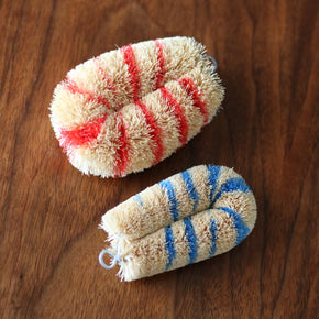 Pair of Japanese Striped Tawashi pot scrub brush on dark wood table.