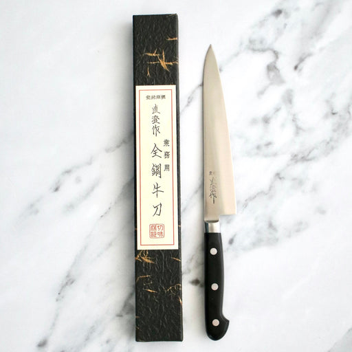 Japanese Naozumi Nihonkou 15cm Sharp Carbon Steel Kitchen Knife and packaging on marble bench.