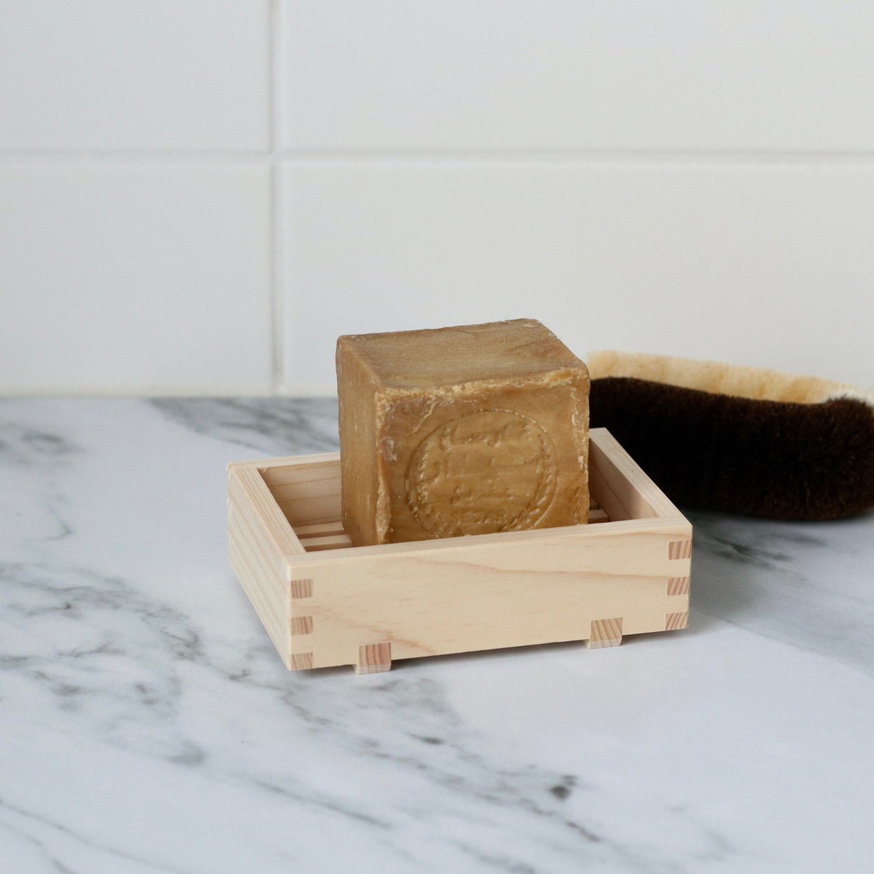 Japanese Hinoki Soap Holder on marble bench with Alepp soap and Japanese scrubber.