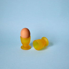 Brown egg in a yellow egg cup on a light blue background