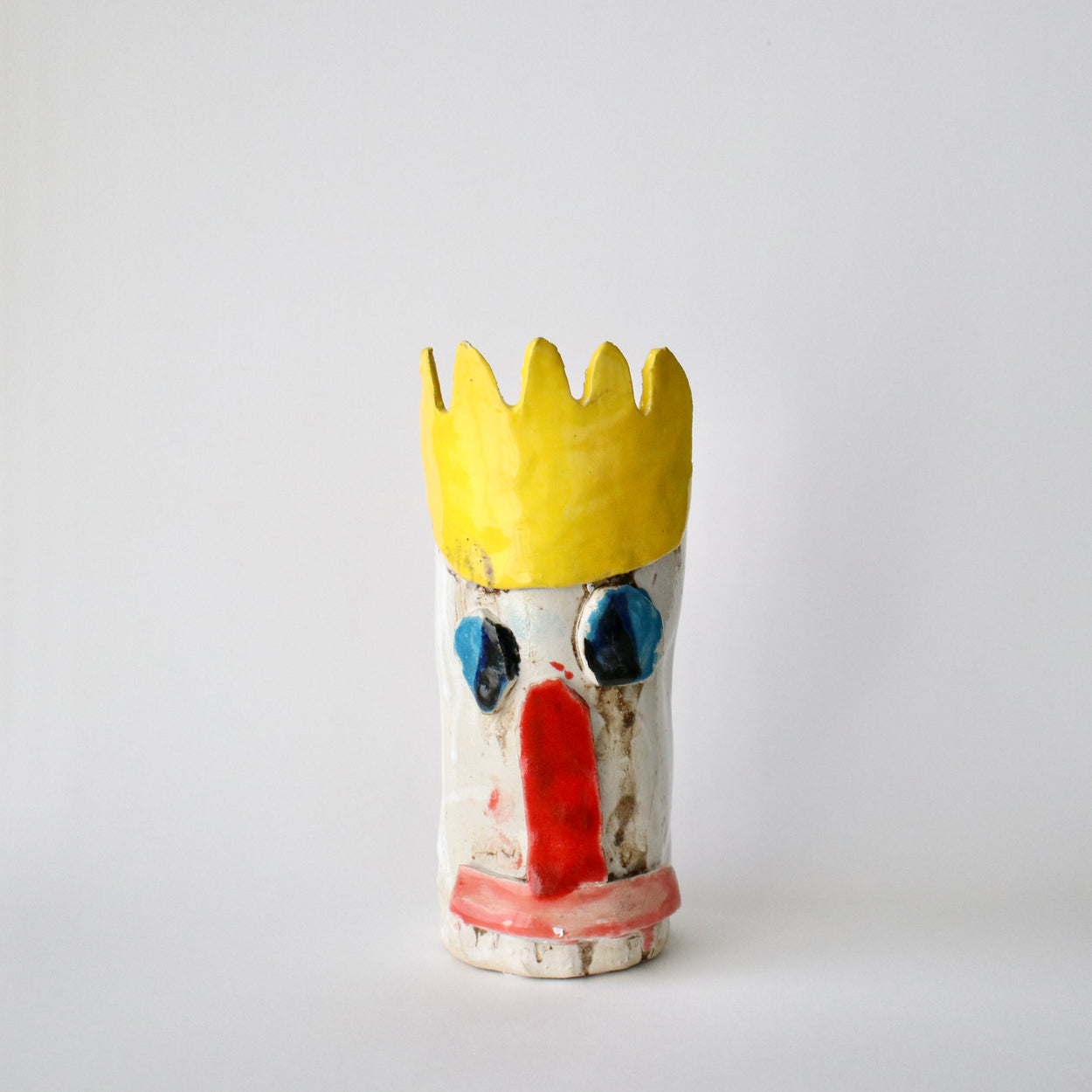 Ceramic vase with a yellow crown-like top on a white background