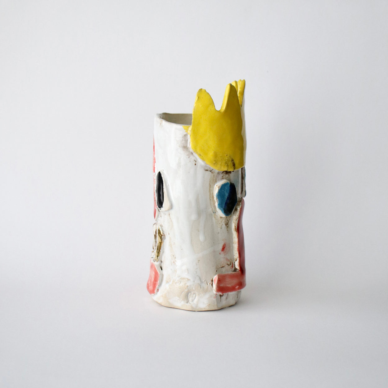 Ceramic vase with a yellow crown on a white background