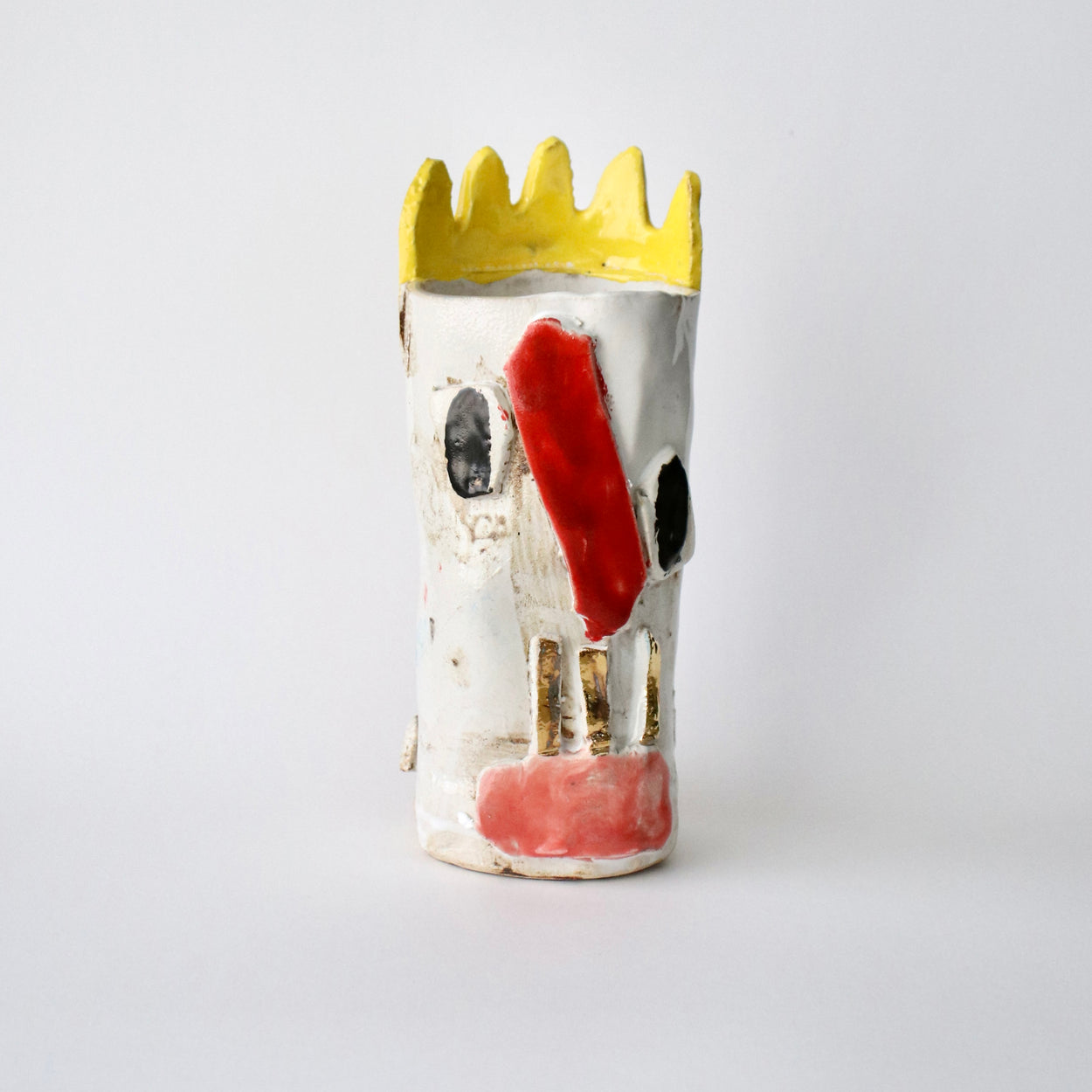 Ceramic vase with a face design on a white background