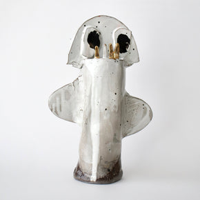 Ceramic sculpture of a ghost with black eyes and gold accents on a white background
