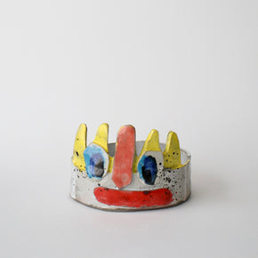 Ceramic piece with colourful face design on a white background
