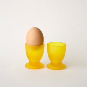Yellow egg cup with a brown egg on a white background