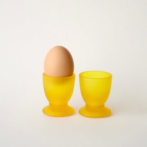 Yellow egg cup with a brown egg on a white background