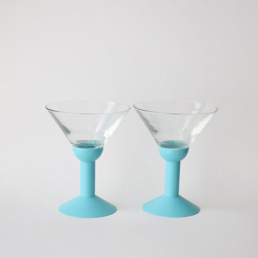 Two martini glasses with light blue bases on a white background