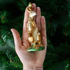 Gold kangaroo ornament held in a hand with a Christmas tree background